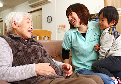 ソファでくつろぐご利用者とスタッフ、お子さんの団らんの様子
